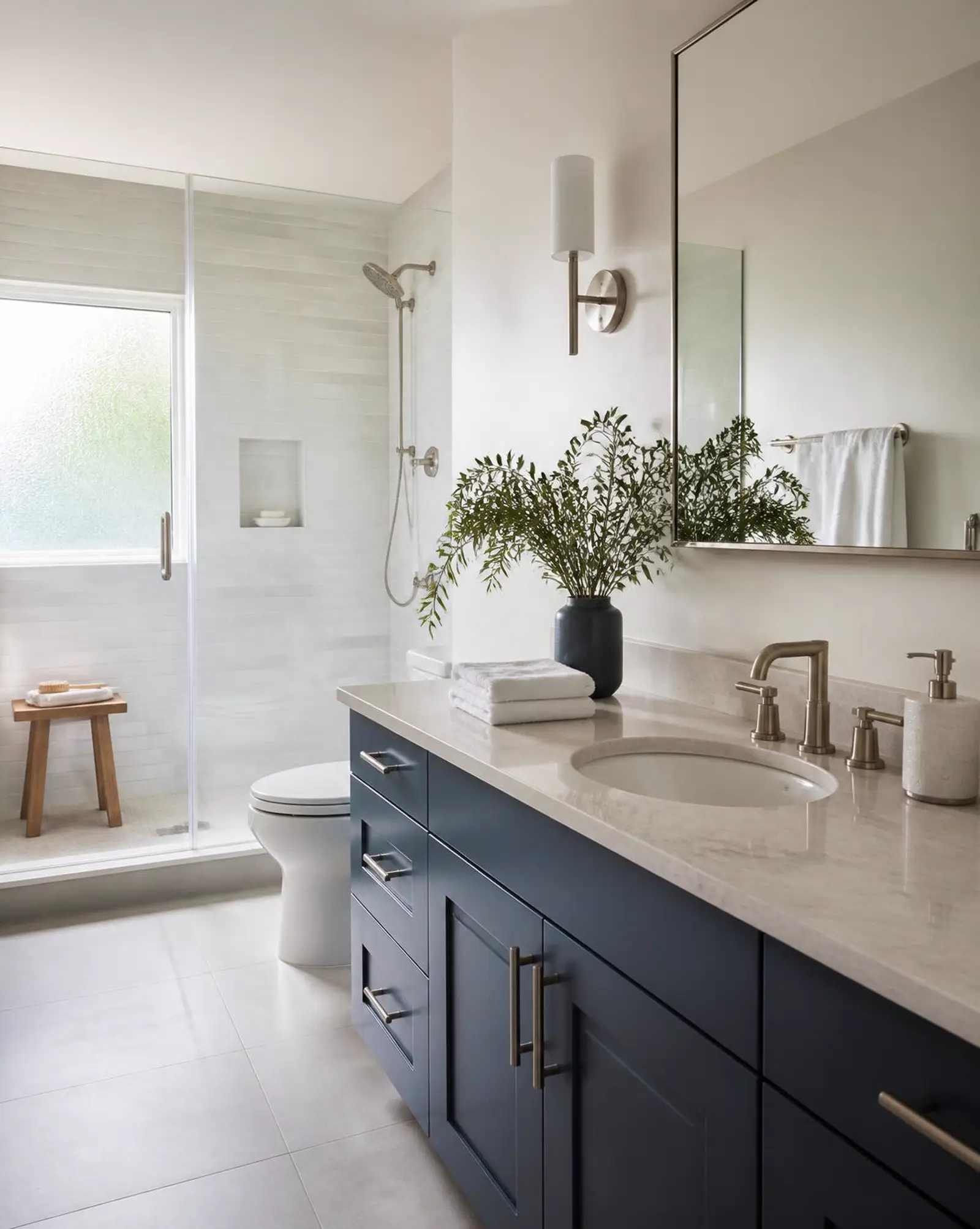 A bright bathroom with a streak-free glass shower, folded towels and a wiped stone vanity.